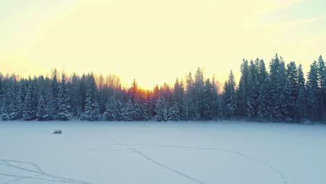 Goldener-Himmel-Bei-Sonnenaufgang-über-Dem-Wald,-Verschneites-Land-Mit-Thermoholzhütte-Und-Fasssauna-Im-Winter