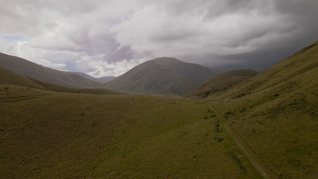 nubes oscuras y pesadas bajas sobre un exuberante paisaje montañoso en nueva zelanda