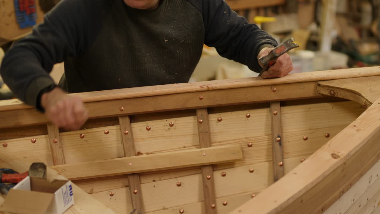 Hammering copper nails securing covering boat wooden boat built