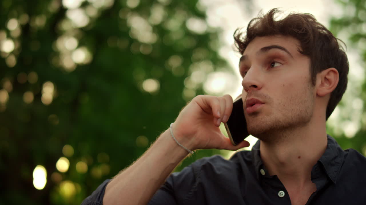 retrato de un hombre serio teniendo una conversación telefónica al aire libre.