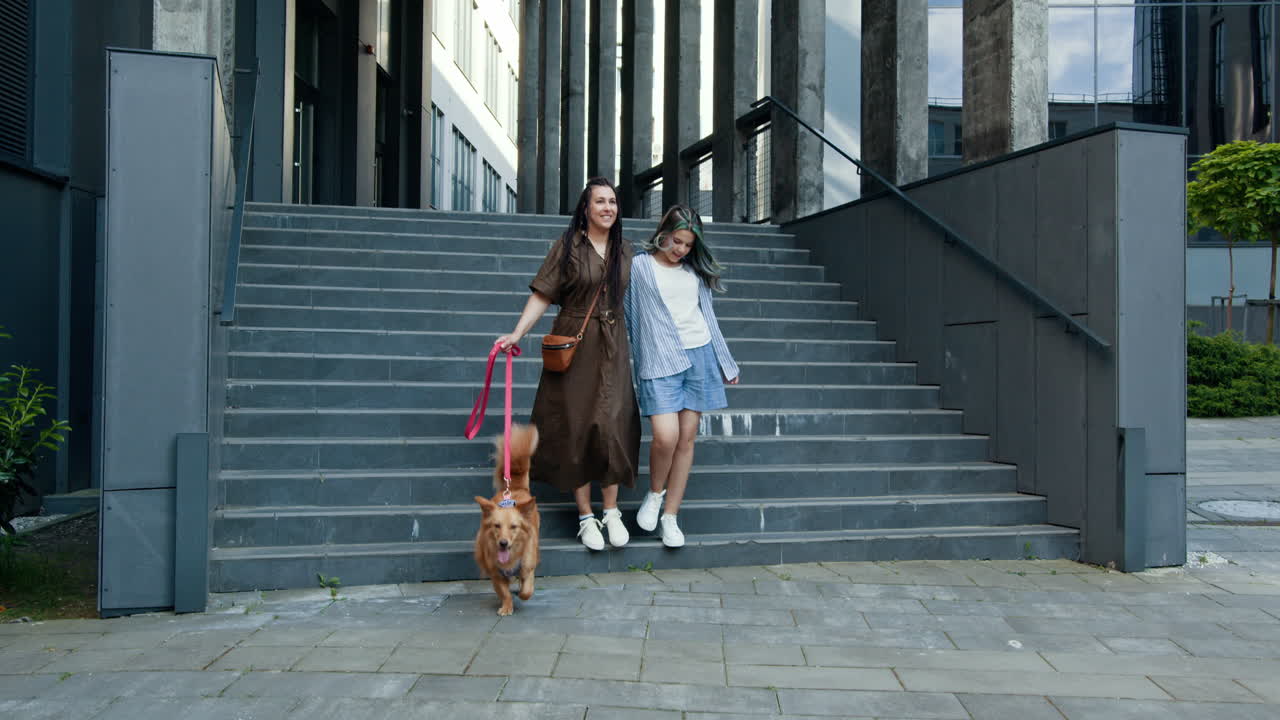 Dos mujeres con su perro paseando por unas escaleras de la ciudad