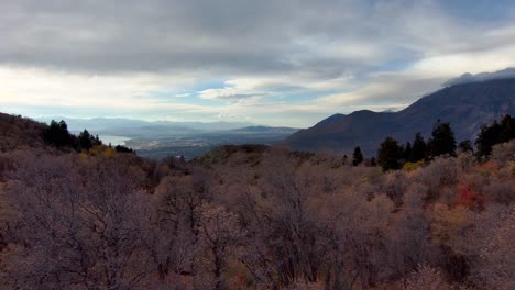 Looking-at-the-distant-town-from-high-in-the-mountains-during-autumn---aerial-pull-back-view