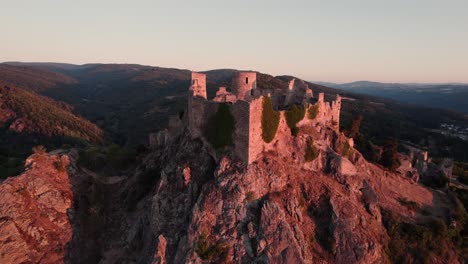 drone-shot-tilting-down-on-the-Castle-of-Couzan-at-sunrise,-french-fortress-in-Loire-departement,-French-countryside