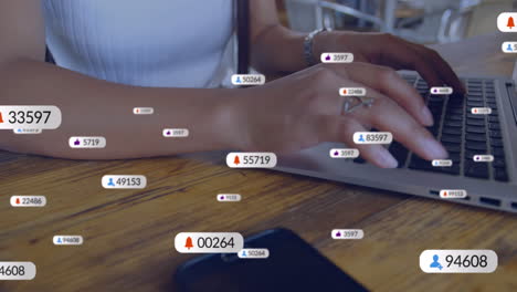 Animation-Von-Social-Media-Symbolen-Vor-Dem-Mittelteil-Einer-Frau,-Die-Im-Büro-Einen-Laptop-Benutzt