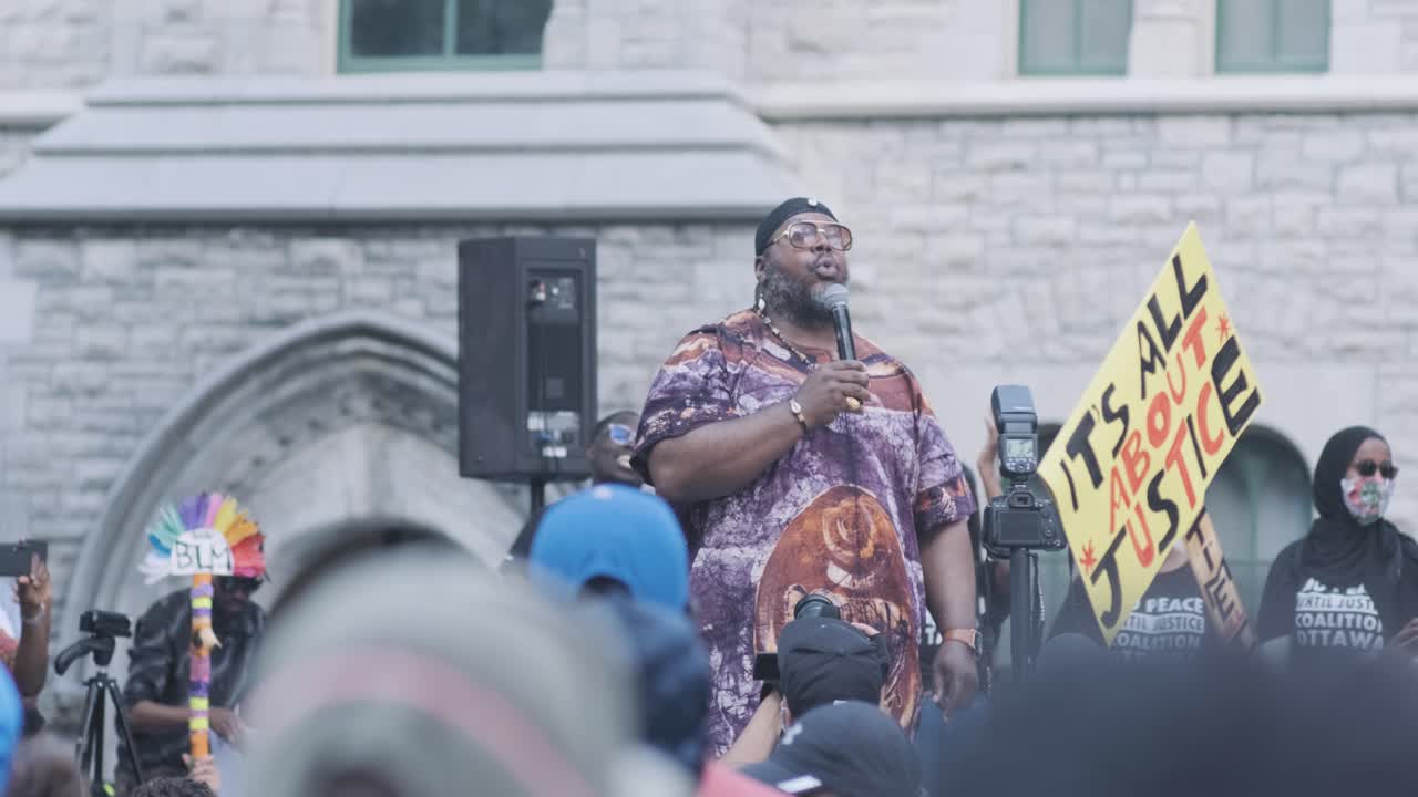 Black leader speaking in front of a Black Lives Matter protest in Ottawa, Ontario