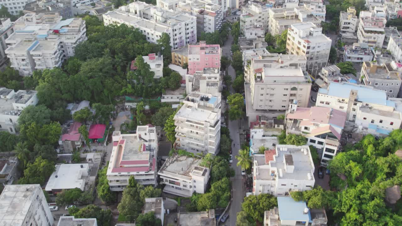 Aerial video of a typical Indian city's and street view with moving car surrounded by trees and buildings, apartements