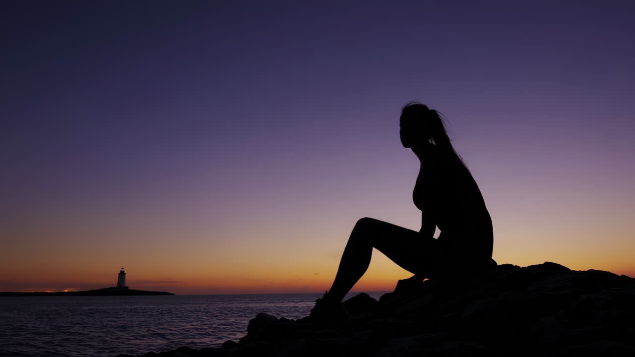 Woman Silhouetted at Sunset on the Coast