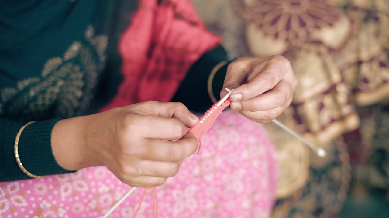 공예용 바늘과 붉은 양모로 된 인도 여성의 손을 닫습니다