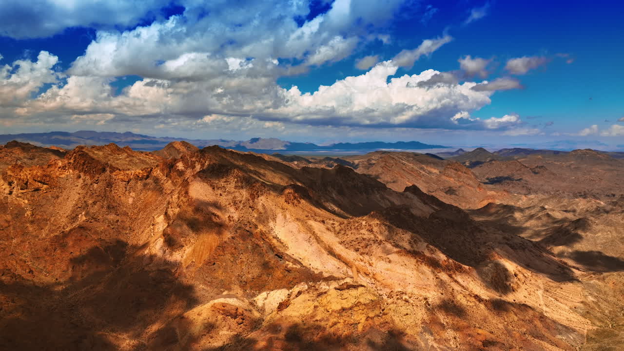 Beautiful fluffy clouds throw their shadows on the bare rocks. Scenic view of the mountains in Mojave desert.