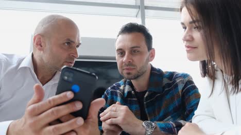 three business people looking at a smartphone