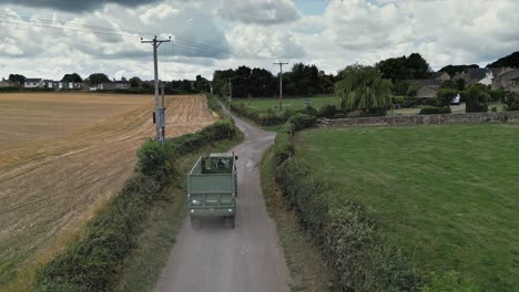 rural aerial scene with a tractor driving down a country lane, surrounded by fields and farmland