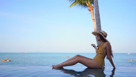 Woman-in-yellow-bathing-suit-sitting-at-the-edge-of-a-swimming-pool