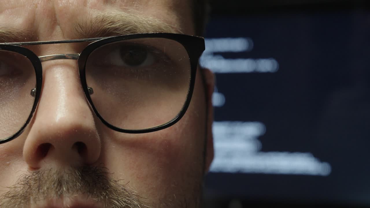 Close-up of a man watching as code appears on the screen behind him—symbolizing how AI takes over programming tasks and automates digital work silently in the background