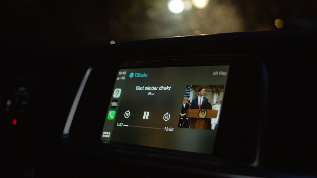 Listening to car audio radio news station reporter talking talk podcast discussing subject driving cars taxi driver music entertainment digital analog night time evening display dark city interior