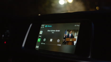 escuchando auto audio radio noticias estación reportero hablando hablar podcast discutiendo tema conduciendo autos taxista música entretenimiento digital analógico noche pantalla noche oscuro ciudad interior