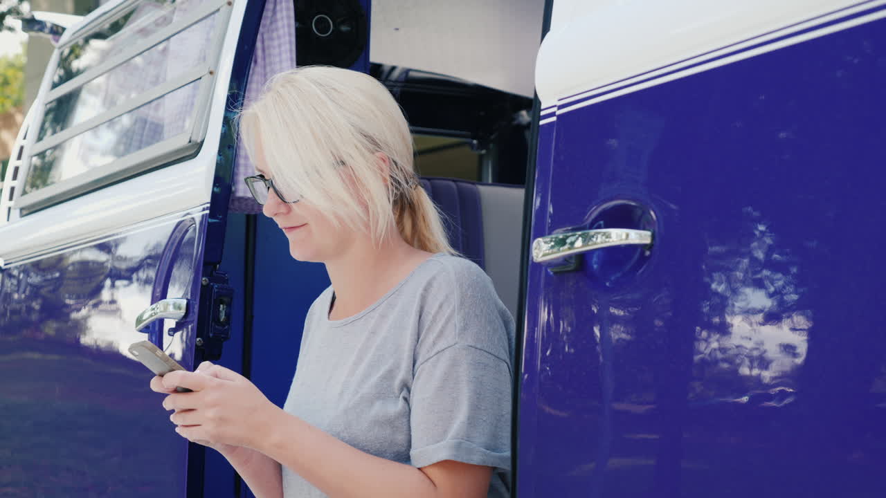 mujer enviando mensajes de texto en una autocaravana retro