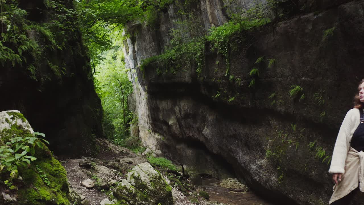 mujer explorando un cañón rocoso en un bosque
