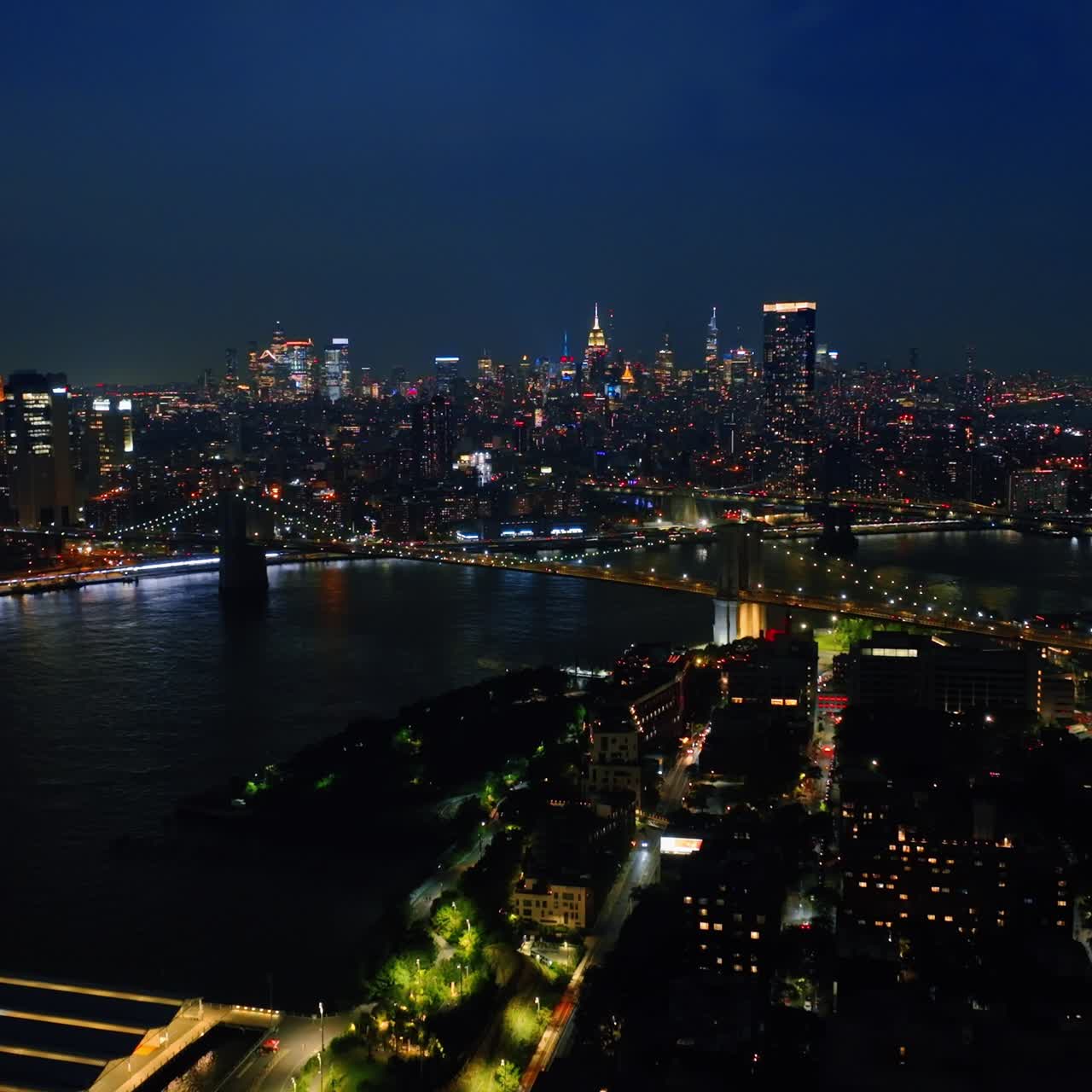 Panorama of luminous New York and the East River at night time. Lively vibrant city view from top