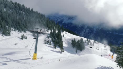 A-view-from-afar-of-the-ice-flyers-that-are-moving-up-down-the-slopes-of-the-Alps,-above-the-snowy-mountains-slopes-of-Engelberg,-in-Brunni,-Switzerland