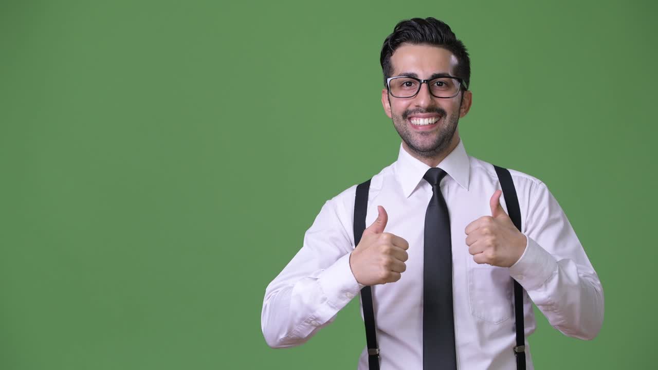 joven empresario persa barbudo y guapo contra un fondo verde