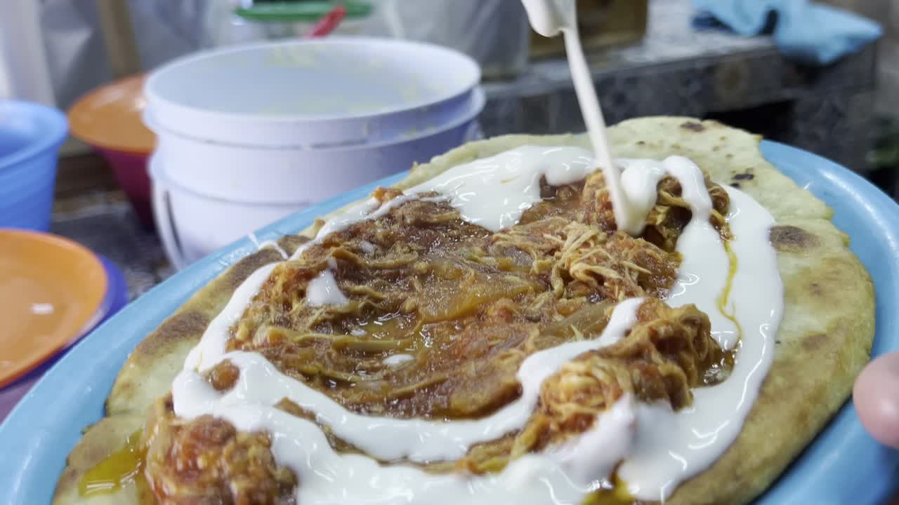 Traditional Mexican huarache with shredded meat and sauce served on a colorful plate
