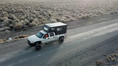 truck driving on a dirt road in the desert, aerial tracking spinning shot