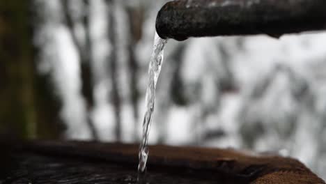 agua cayendo en cámara lenta de una tubería de una fuente en el bosque en suiza