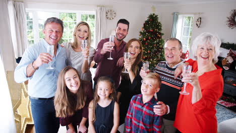 portrait of multi-generation family and friends celebrating with champagne at christmas house party