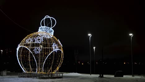 large illuminated christmas ornament in a winter park at night