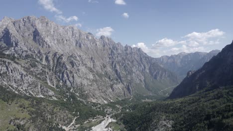 Frontales-Drohnenvideo,-Das-Sich-Zwischen-Den-Bergen-Auf-Der-Straße-Azem-Hajdari-Im-Valbona-Tal-Und-Dem-Fluss-Rrogam-I-Shales-Fortbewegt