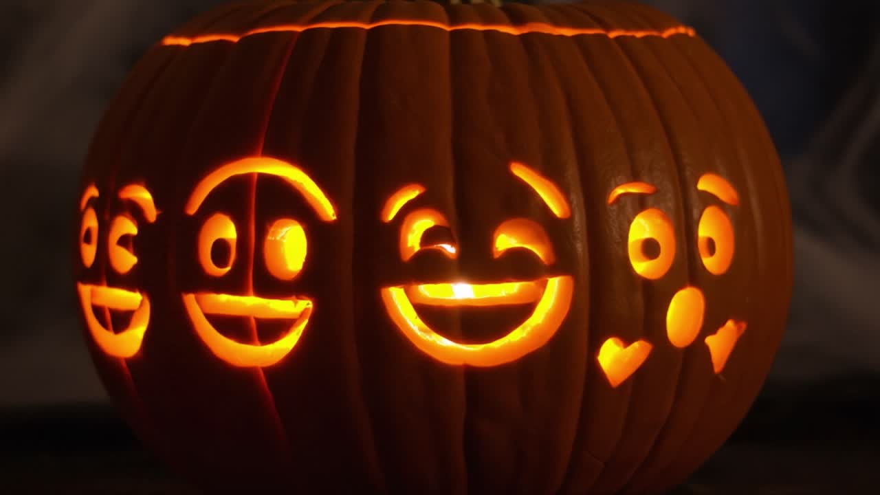 A Spooky Display of Expressions: A Halloween Pumpkin Carved with Various Emoji Faces Illuminated from Within for a Festive Seasonal Effect