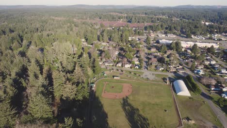 Hermosa-Toma-Aérea-De-4k-Mirando-Hacia-El-Campo-De-Béisbol-Local-Con-Jugadores-En-Bandon,-Oregon