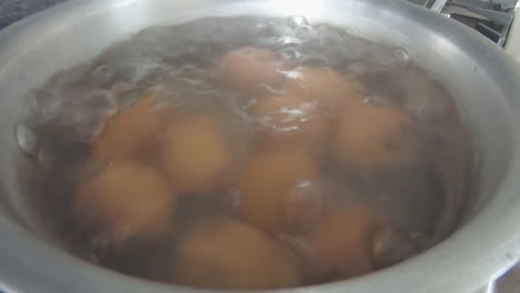 eggs slowly coming to boil in water in silver pot pan