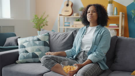 young woman relaxing on couch with chips