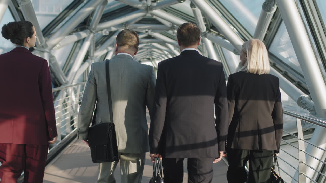 Business People Walking Along Glass Bridge