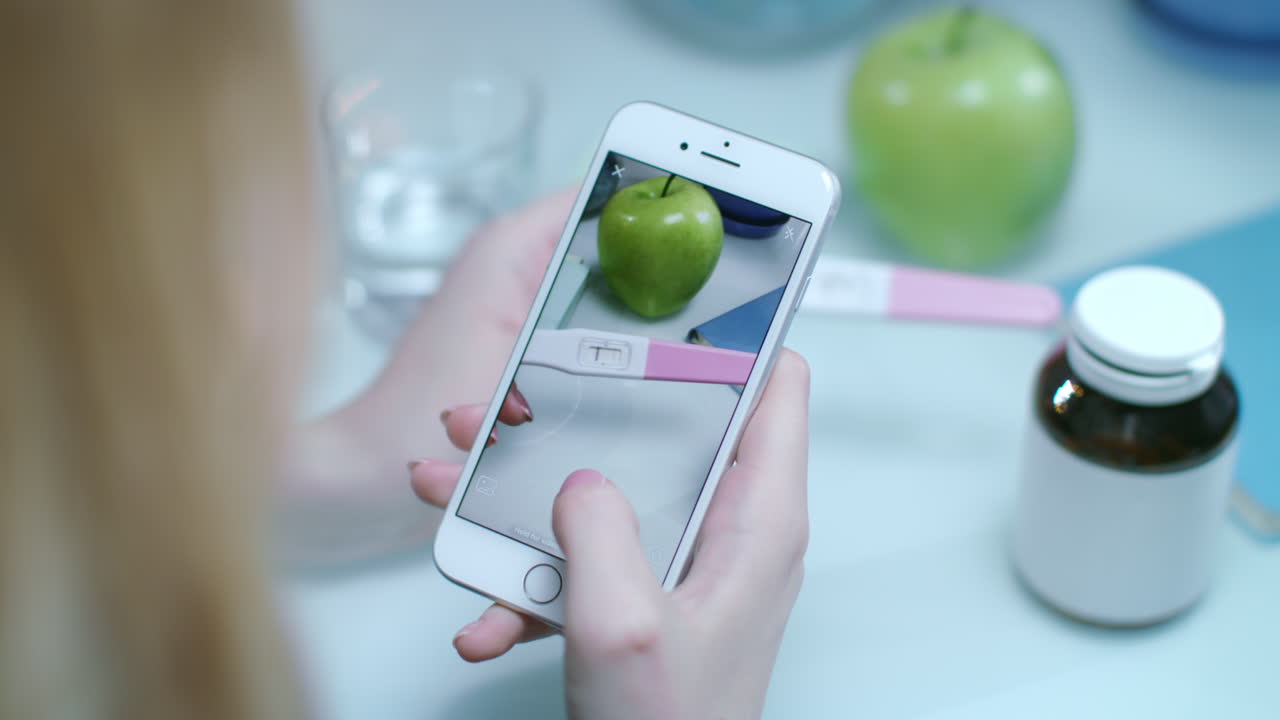 여성이 긍정적인 임신 테스트의 모비 사진을 찍고 있습니다. 임신 개념