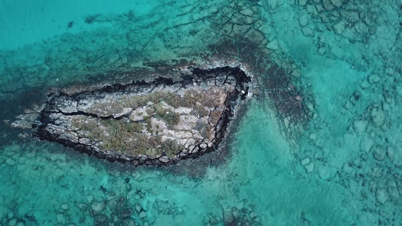 새가 왼쪽에서 오른쪽으로 날아갈 때 그리스 크레타 엘라포니시 해변 근처 지중해에 있는 바위 섬의 멋진 공중 드론 줌 아웃 샷