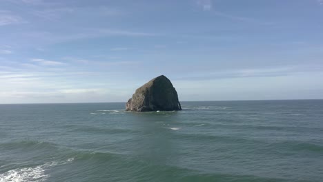 Drone-Volando-Bajo-Sobre-El-Agua-Directamente-Hacia-La-Roca-Del-Pajar-En-Pacific-City,-Costa-De-Oregon