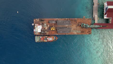 ascending aerial shot of industrial pipe boat docking on harbor of gili trawangan,asia