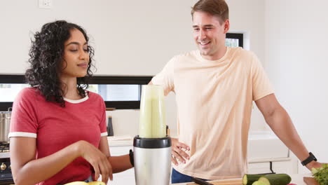 blending smoothie, young multiracial couple enjoying healthy drink preparation in kitchen, at home