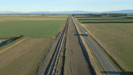 la autopista estatal 73 de nueva zelanda conduce vehículos rodeados de montañas y granjas.