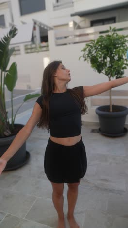 young woman practicing gymnastics with a blue ball on a patio