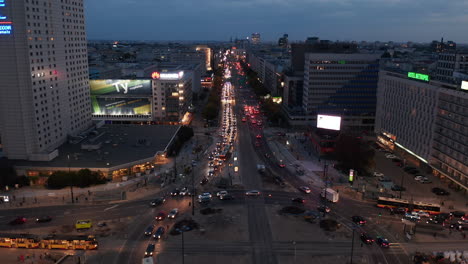 Descending-footage-of-busy-multilane-road-and-large-roundabout-in-city-centre.-Evening-rush-hour-on-wide-boulevard.-Warsaw,-Poland