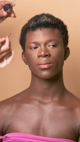 visagiste applying lipstick while doing makeup on transgender preparing for photo shoot. . vertical footage