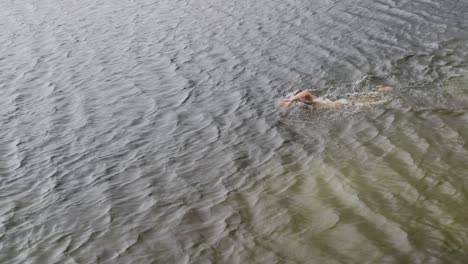 caucasian man having a good time on a trip to the mountains, wearing swimming trunks and swimming in