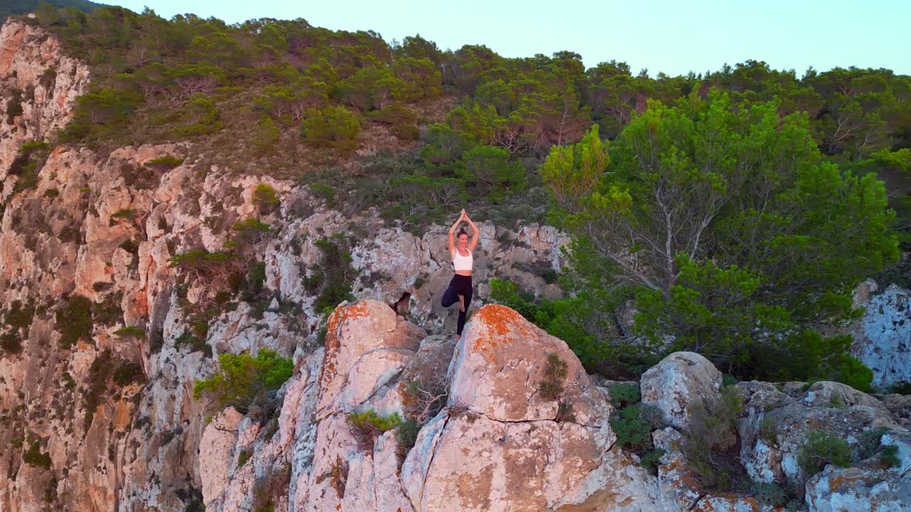 impresionante vista aérea de arriba vuelo ibiza acantilado yoga árbol pose modelo chica puesta de sol por la noche