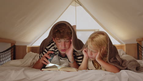 siblings reading in a tent bed