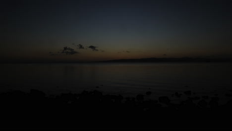 A-magnificent-tranquil-sunset-with-fast-moving-clouds,-facing-the-open-sea-with-a-small-fishing-boat-briefly-passing-by