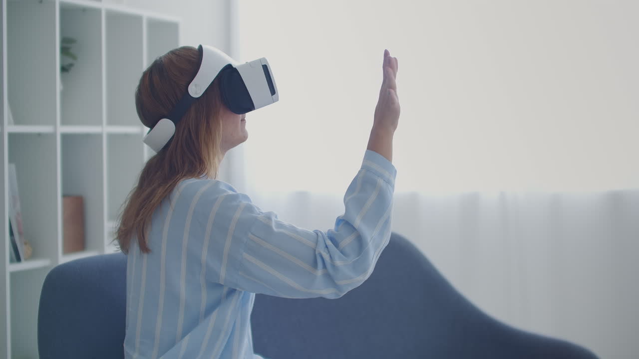 Young girl in virtual reality headset scrolling in air at home Technology concept.