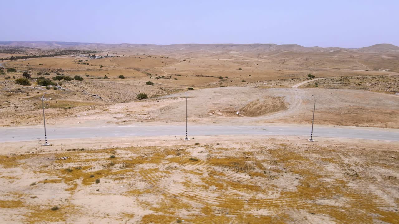 un camino en el medio del desierto en el negev, sur de israel colinas marrones cielo azul